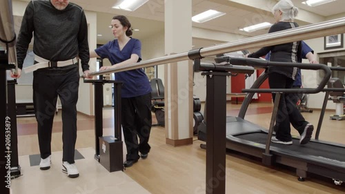Medium shot of a senior man walking in parallel bars