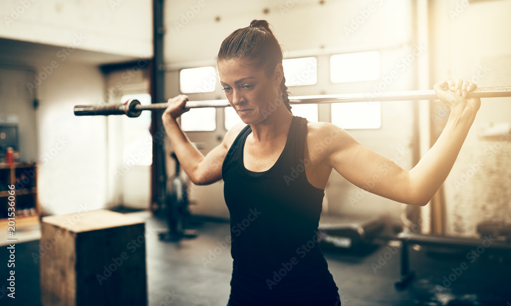 Fit young woman exercising with a barbell in a gym