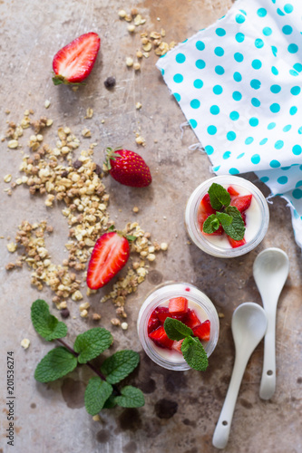 Homemade healthy breakfast with homemade baked granola, fresh strawberry and yogurt on stone or concrete table. Top view flat lay background.