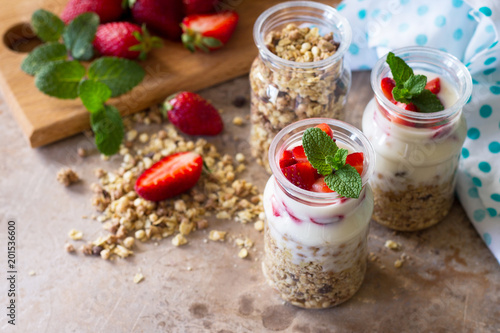 Homemade healthy breakfast with homemade baked granola, fresh strawberry and yogurt on stone or concrete table. Copy space.
