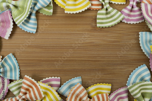 Colorful raw bow-tie  pasta on wooden background with copy space