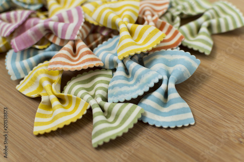 Colorful raw bow-tie  pasta on wooden background with copy space