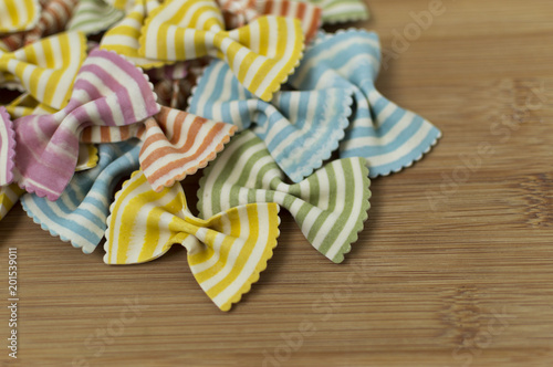 Colorful raw bow-tie  pasta on wooden background with copy space