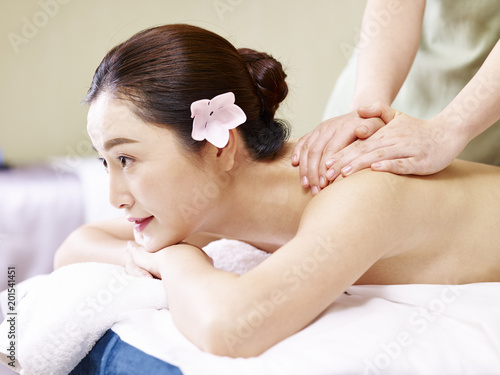young asian woman receiving massage in spa salon