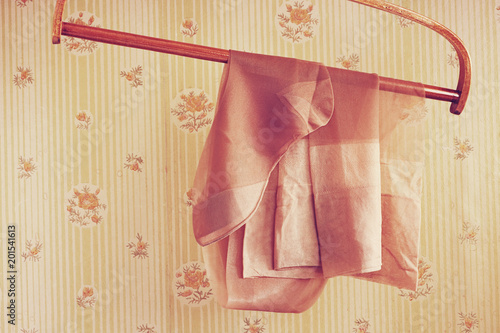 Vintage silk stockings on the wooden hanger against a background of the old wallpaper © Lena Lir