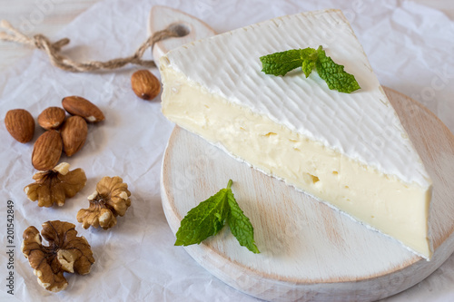 Fresh Brie cheese  on a wooden board with nuts