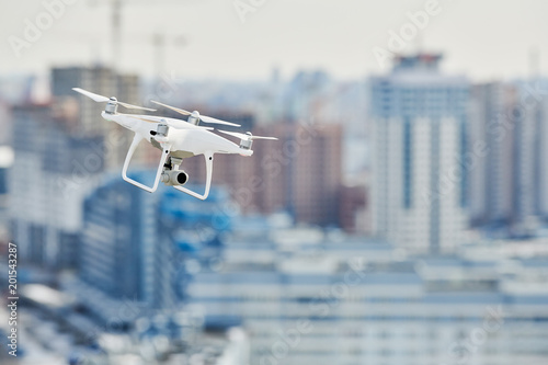 drone quadcopter with digital camera hovering over city