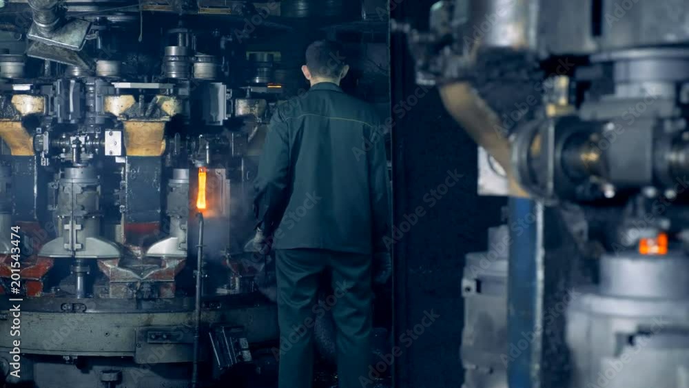 A worker watches how special machine melts out bottles at a plant. 4K. A worker watches how special machine melts out bottles at a plant. 4K.