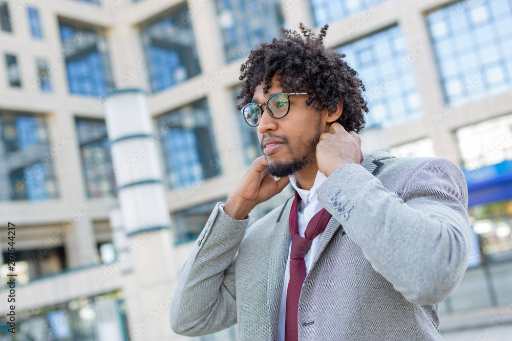 Beautiful young business man fixing tie at work