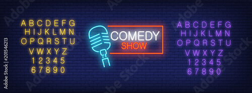Neon alphabet and Comedy Show lettering with mike in frame on brick background. Show, nightclub, comedy club. Advertisement concept. For signboards, template design, banners