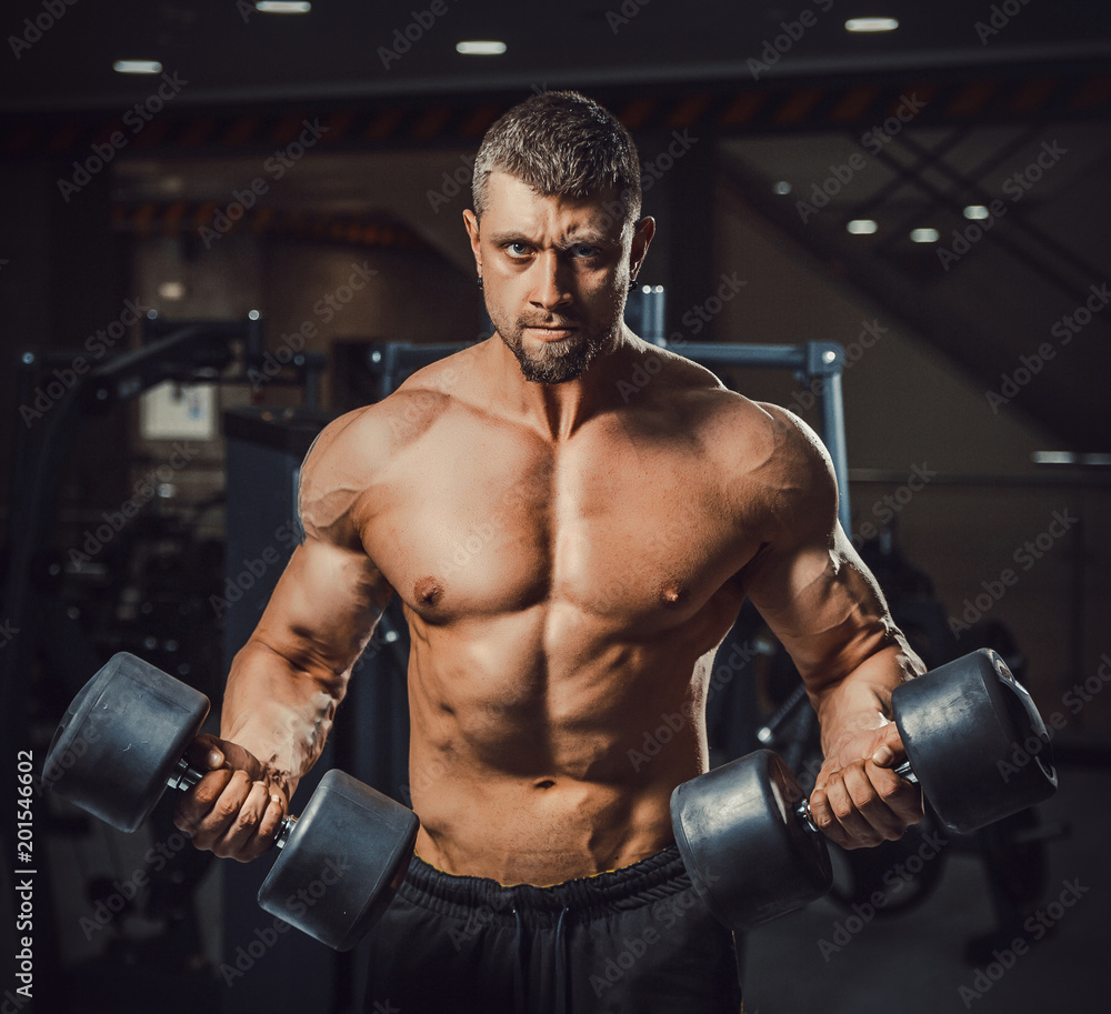 european caucasian athletic man bodybuilder holding dumbell and showing his muscular arms. man doing exercise for biceps. Biceps workout clouse-up. at once two dumbbells