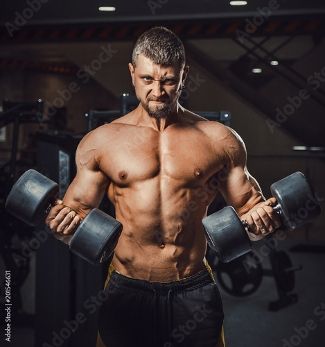 european caucasian athletic man bodybuilder holding dumbell and showing his muscular arms. man doing exercise for biceps. Biceps workout clouse-up. at once two dumbbells