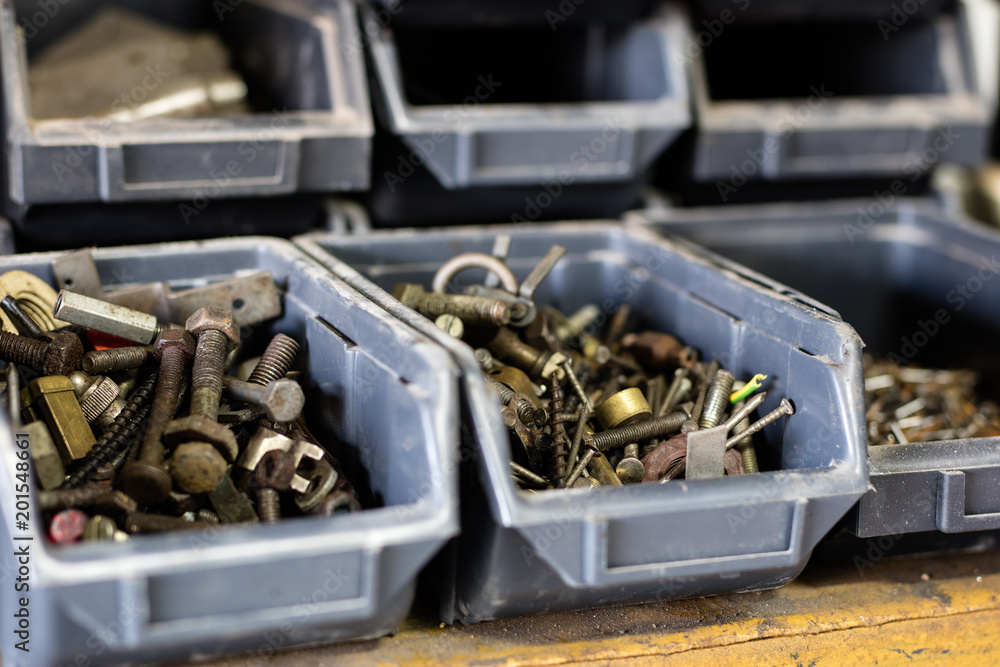 Metal screws in storage containers. Shelf locksmith workshop with parts for mechanical repairs.