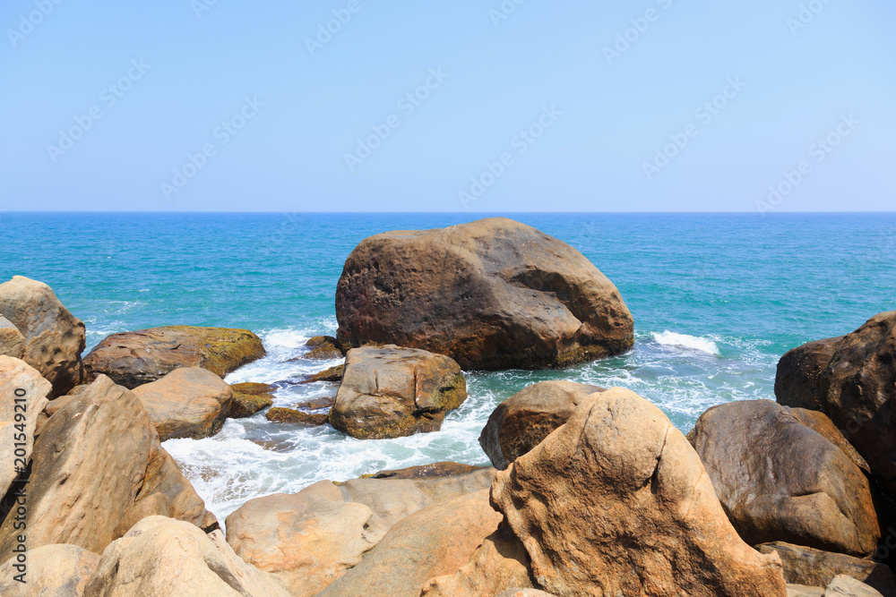 ocean waves wash the rocks of a tropical beach