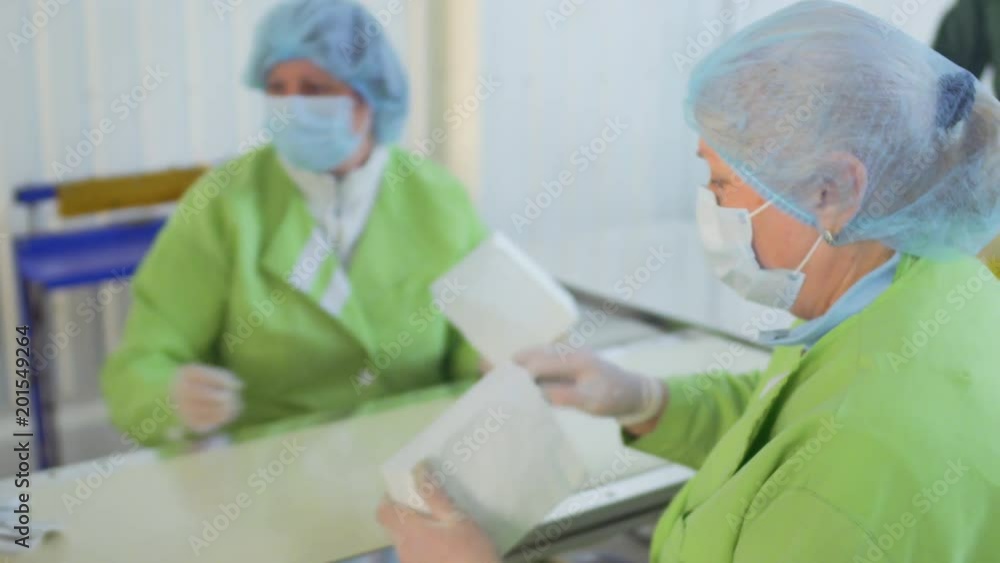 Two workers packs tea bags inside packages Two workers packs tea bags inside packages