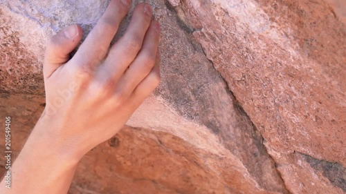 Closeup slow motion video of a hand reaching and grabbing a rock handhold during outdoor rock climbing