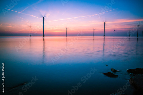 Sun setting over the water in Holland with red light full of rigging marks in the sky