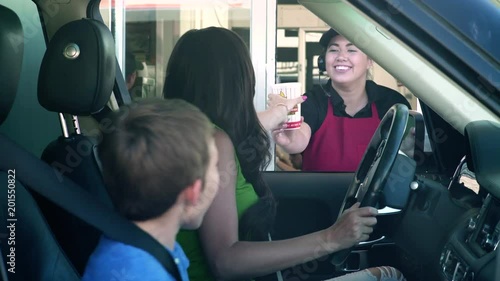 Mother and son receiving food order from employee of a fast food drive-through
