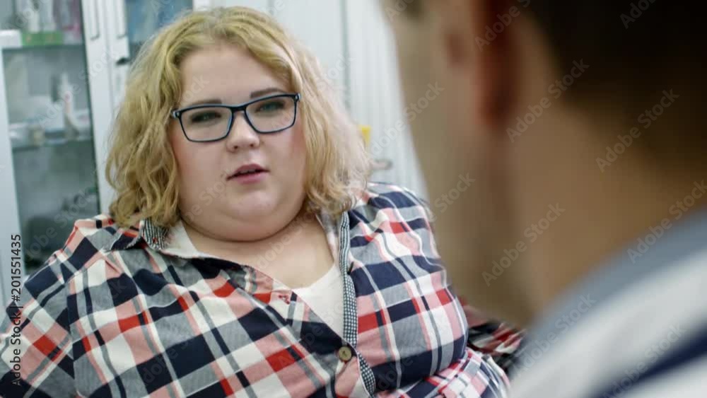 Tilt down of male doctor showing glucose meter to overweight female patient and explaining its results Tilt down of male doctor showing glucose meter to overweight female patient and explaining its results