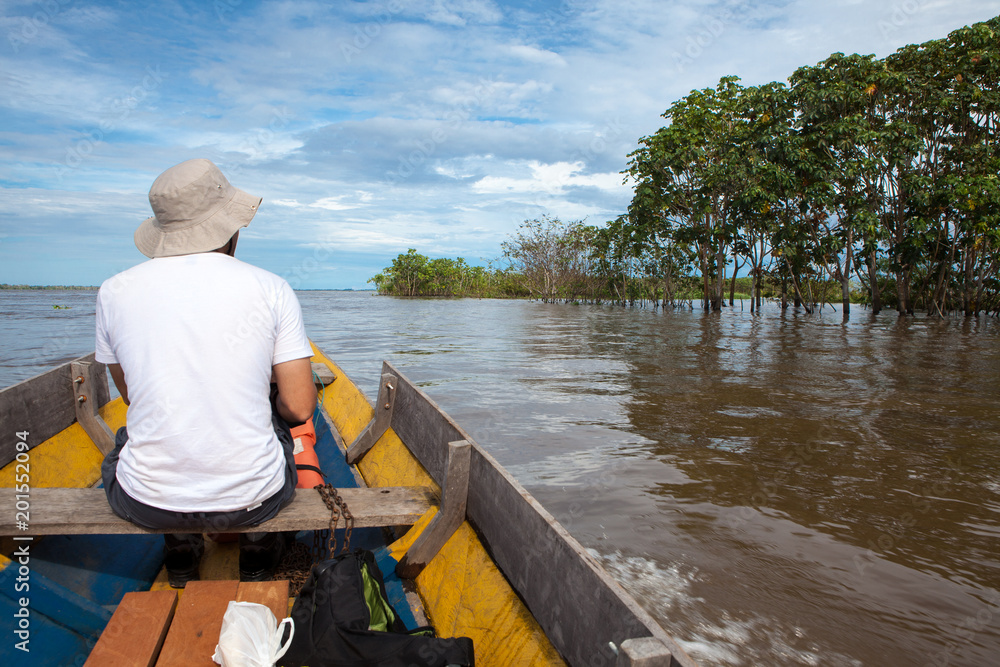 Traditional boat traveler looking at the view of the Amazon River.