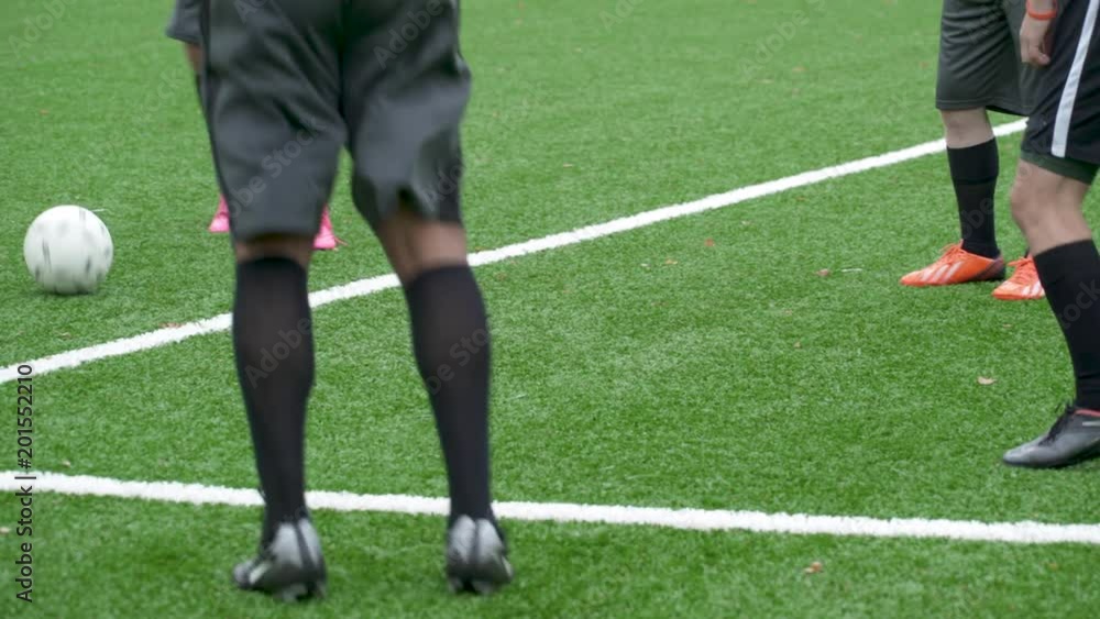 Male soccer players lower section standing in circle passing ball.