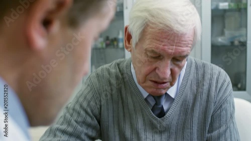 Wallpaper Mural Tilt down of male physician in lab coat holding tablet and showing document to senior patient Torontodigital.ca