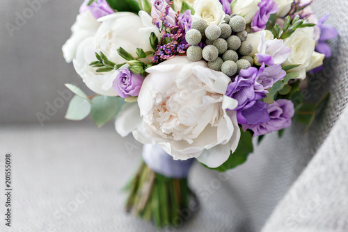 Brides wedding bouquet with peonies  freesia and other flowers on black arm chair. Light and lilac spring color. Morning in room