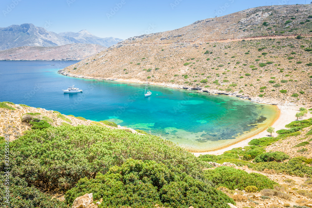 Beautiful sunny holiday coast view to the greek blue sea with crystal clear water beach relaxing with some boats fishing cruising surrounded by hills mountains, Patmos, Kos Island, Dodecanese, Greece