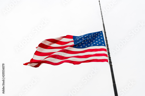 United States Flag Flying at a Half-staff Waving Against Gray Overcast Sky photo