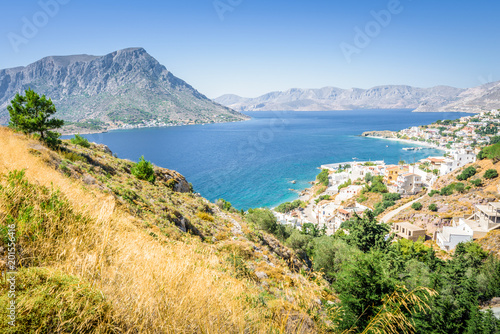 Beautiful sunny holiday view to the greek beach blue sea with crystal clear water beach with some boats fishing cruising surrounded by hills mountains, Kalymnos Island, Kos, Dodecanese, Greece 