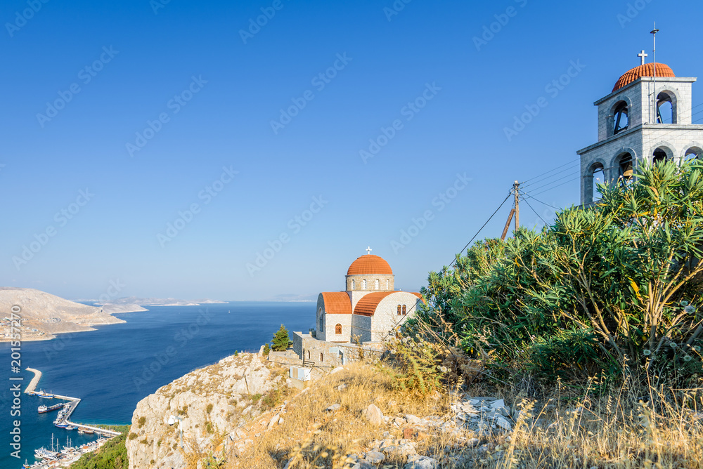Beautiful mediterranean greek colorful holy monastery Agios Savvas situated on a mountain high above the town of Pothia, Kalymnos Island, Kos, Dodecanese, Greece