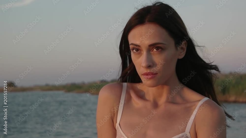 Close up portrait of a girl looking at sunset over ocean. Independent Woman with hair blowing in wind. Young Girl Slow Motion Close up portrait of a girl looking at sunset over ocean. Independent Woman with hair blowing in wind. Young Girl Slow Motion