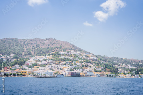 Beautiful sunny greek village town harbor view to the aegean blue sea with crystal clear water boats cruising surrounded by hills mountains windmills, Agia Marina, Leros, Dodecanese Islands, Greece