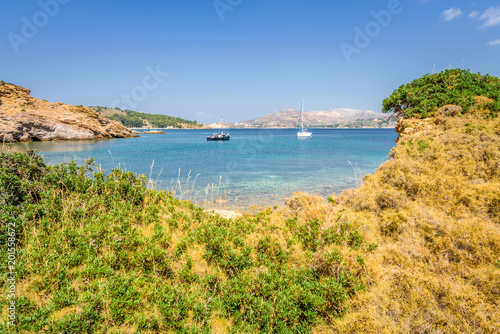 Beautiful sunny coast view to the greek blue sea with crystal clear water beach with some boats fishing cruising surrounded by hills  Kokkina Beach  Leros  Dodecanese Islands  Greece     July 18 2017