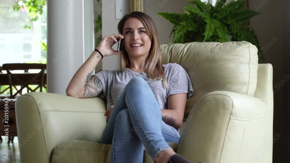 Young woman sitting in armchair talking on mobile phone. Young woman sitting in armchair talking on mobile phone.