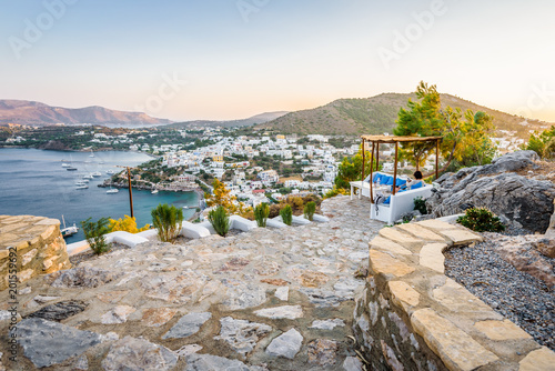 Beautiful sunny greek village town harbor view to the aegean blue sea with crystal clear water boats cruising surrounded by hills mountains windmills on top, Panteli, Leros, Dodecanese Islands, Greece photo