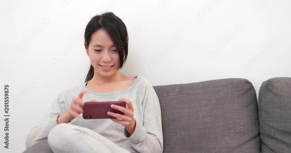 Woman using mobile phone and sitting on sofa