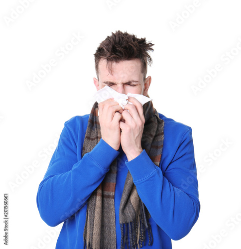 Young man with cold sneezing on white background