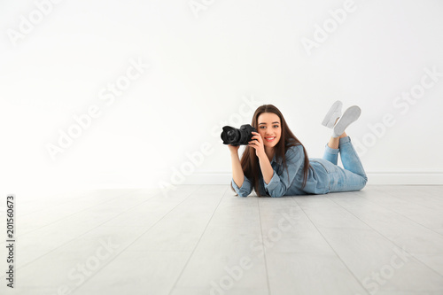 Female photographer with camera lying on floor indoors