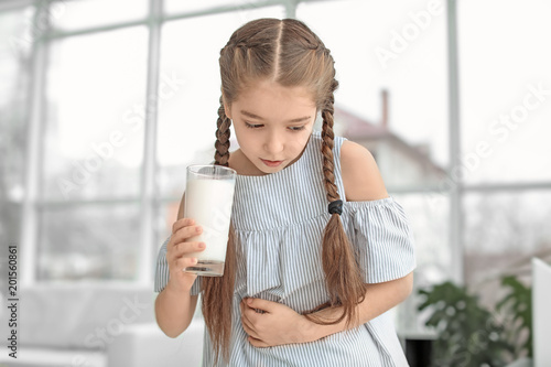 Konstfotografi Little girl with dairy allergy holding glass of milk indoors