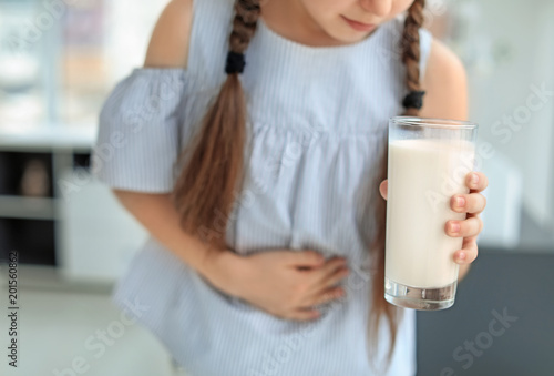 Canvastavla Little girl with dairy allergy holding glass of milk indoors