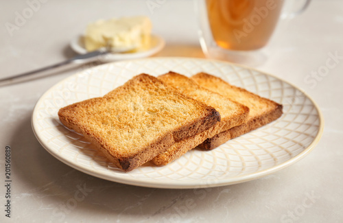 Plate with toasted bread on table