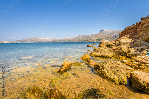 Beautiful sunny coast view to the greek blue sea with crystal clear water beach with some boats fishing cruising surrounded by hills, Kokkina Beach, Leros, Dodecanese Islands/ Greece – July 18 2017 photo