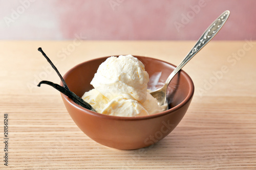 Bowl with tasty vanilla ice cream on wooden table