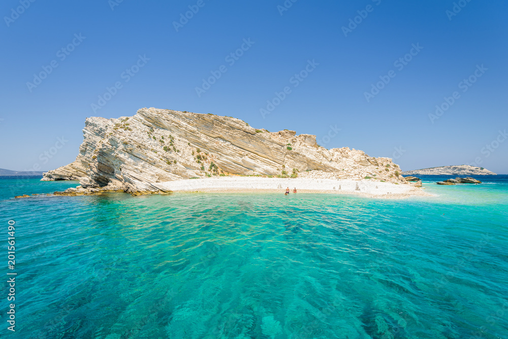 Beautiful sunny coast view to a small greek island and crystal clear blue water beach with some boats cruising and people swimming, White Island, Aspronisi, Leros, Dodecanese/ Greece – July 22 2017 Beautiful sunny coast view to a small greek island and crystal clear blue water beach with some boats cruising and people swimming, White Island, Aspronisi, Leros, Dodecanese/ Greece – July 22 2017