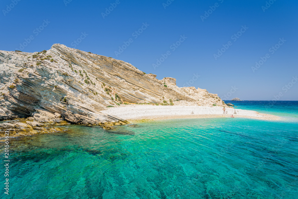 Beautiful sunny coast view to a small greek island and crystal clear blue water beach with some boats cruising and people swimming, White Island, Aspronisi, Leros, Dodecanese/ Greece – July 22 2017 Beautiful sunny coast view to a small greek island and crystal clear blue water beach with some boats cruising and people swimming, White Island, Aspronisi, Leros, Dodecanese/ Greece – July 22 2017