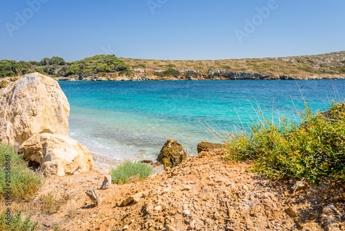 Beautiful sunny coast view to a small greek village harbor white houses with crystal clear blue water beach cruising fishing some boats and hills background, Arki Island, Leros, Dodecanese, Greece © Thomas Jastram