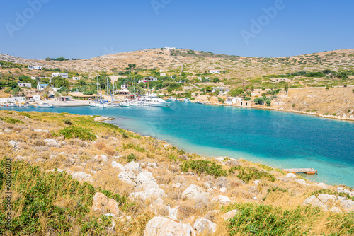 Beautiful sunny coast view to a small greek village harbor white houses with crystal clear blue water beach cruising fishing some boats and hills background, Arki Island, Leros, Dodecanese, Greece © Thomas Jastram