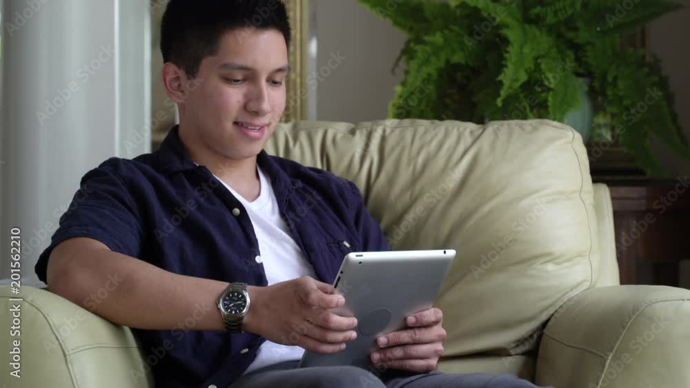 Young man sitting in armchair using digital tablet. Young man sitting in armchair using digital tablet.