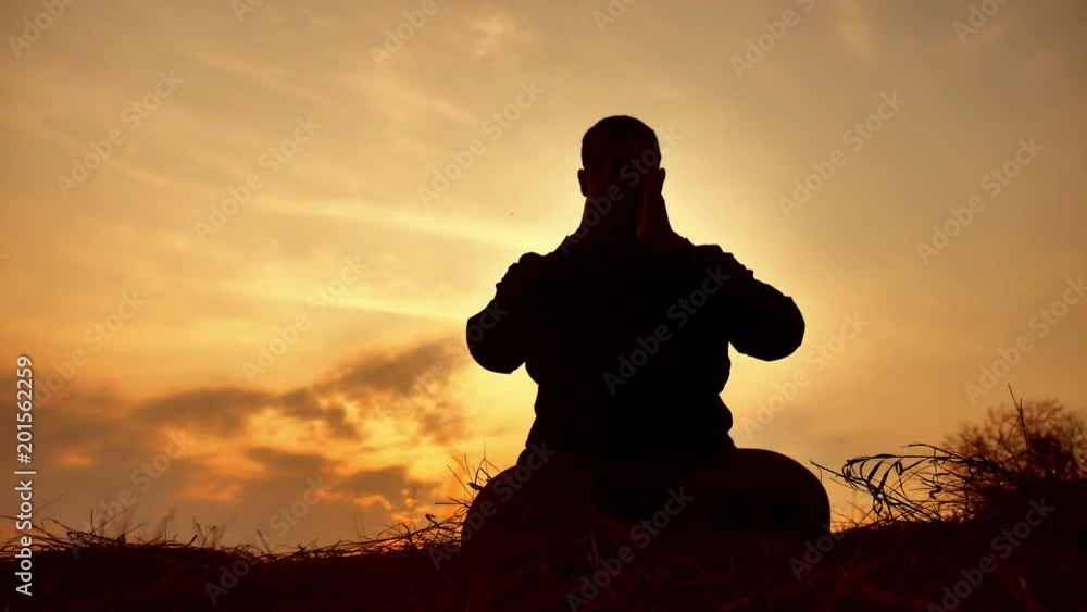 silhouette of a male monk engaged in meditation at sunset sunlight. Buddhist lifestyle prays at sunset healthy way of life nature silhouette of a male monk engaged in meditation at sunset sunlight. Buddhist lifestyle prays at sunset healthy way of life nature